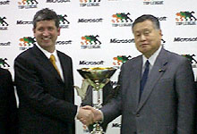 マイクロソフトカップをはさんで握手を交わすヒューストン社長と森会長